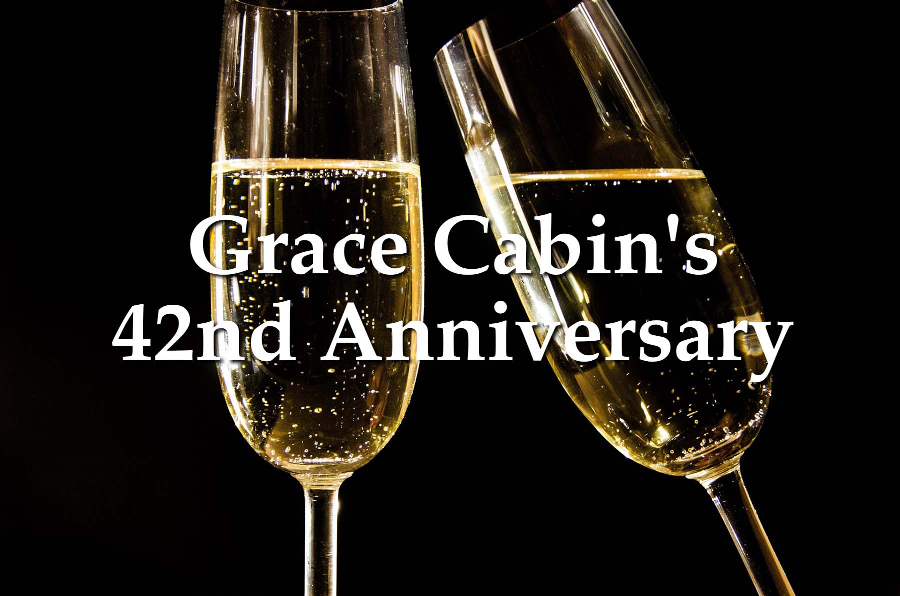 スパークリングワイングラスを背景にしたGrace Cabin's 42nd Anniversaryのテキストイメージ
